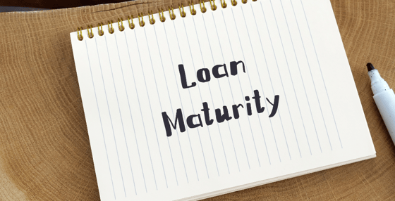 An open notebook sitting on a desk, with “Loan Maturity” written on the first page in black ink.