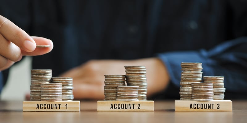 Photo of businessman stacking coins in different piles to represent portfolio diversification strategies